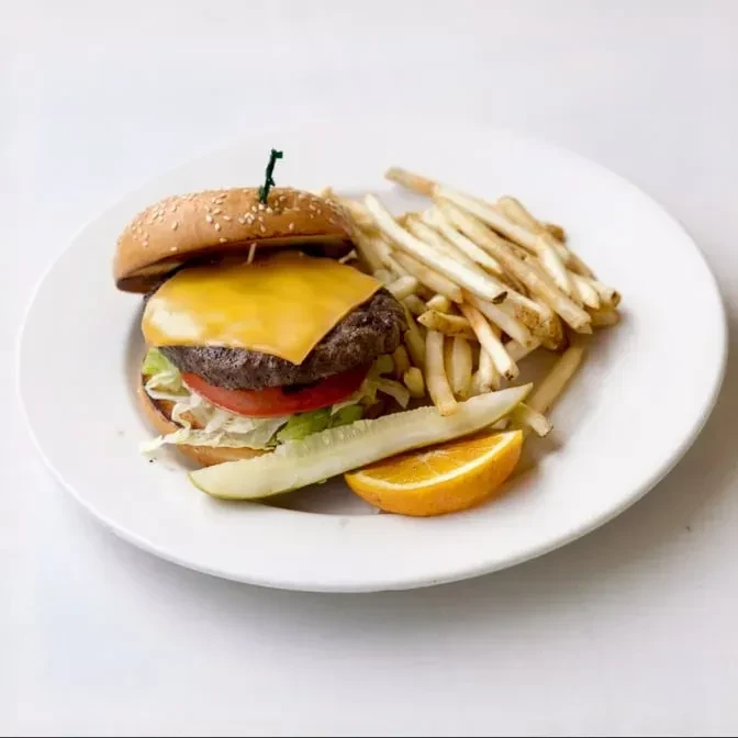 Cheeseburger, fries, pickle, and orange wedge on a white plate.