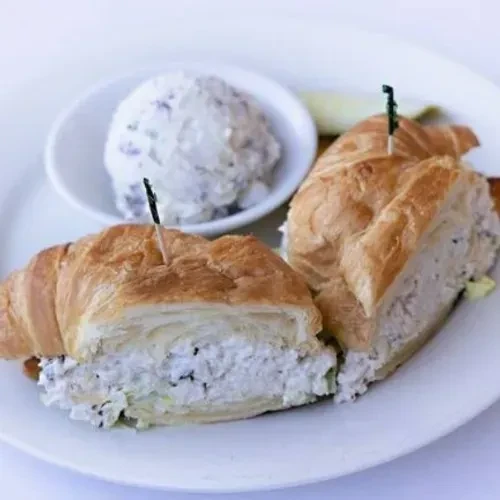 Two chicken salad croissant sandwiches with a side of potato salad.