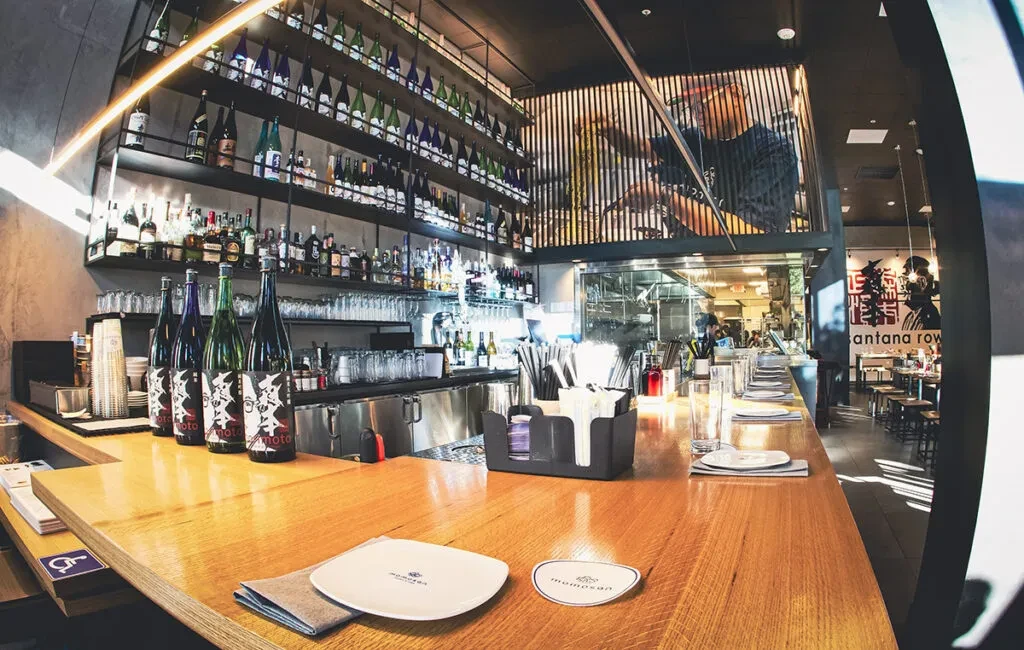 An empty modern bar with rows of bottles and a large wall mural.