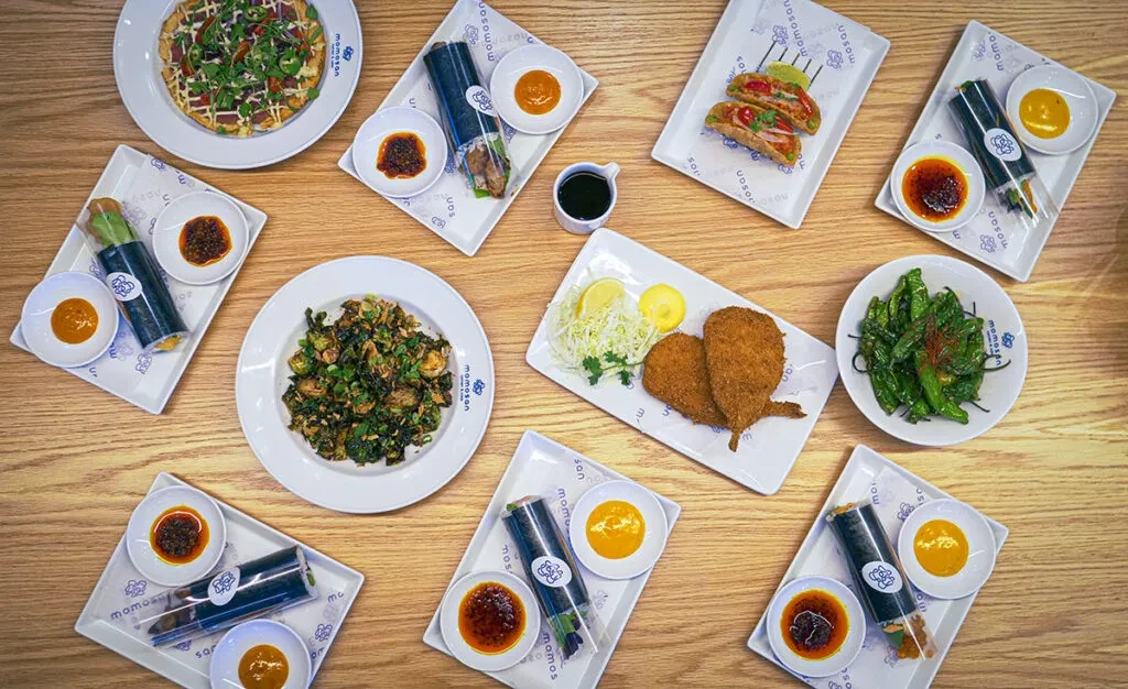 Overhead view of a wooden table laden with various Asian dishes.