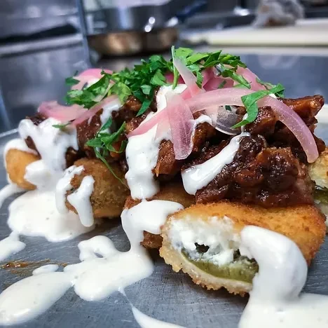 Deep-fried jalapeños with pulled pork, pickled onions, and white sauce.