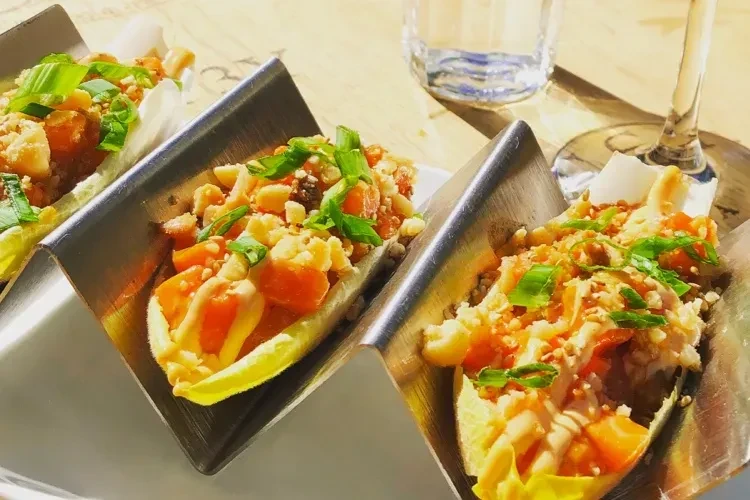 Lettuce wraps with chopped peanuts, vegetables, and dressing in holders.
