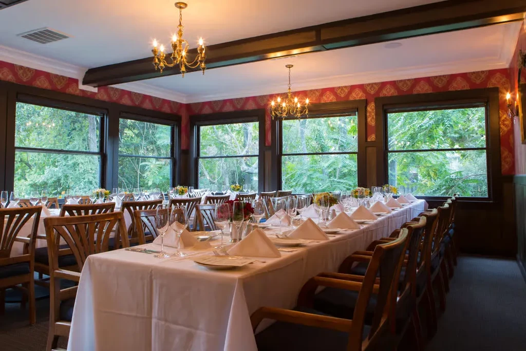 Formal dining room with long white tablecloths, set for many guests.