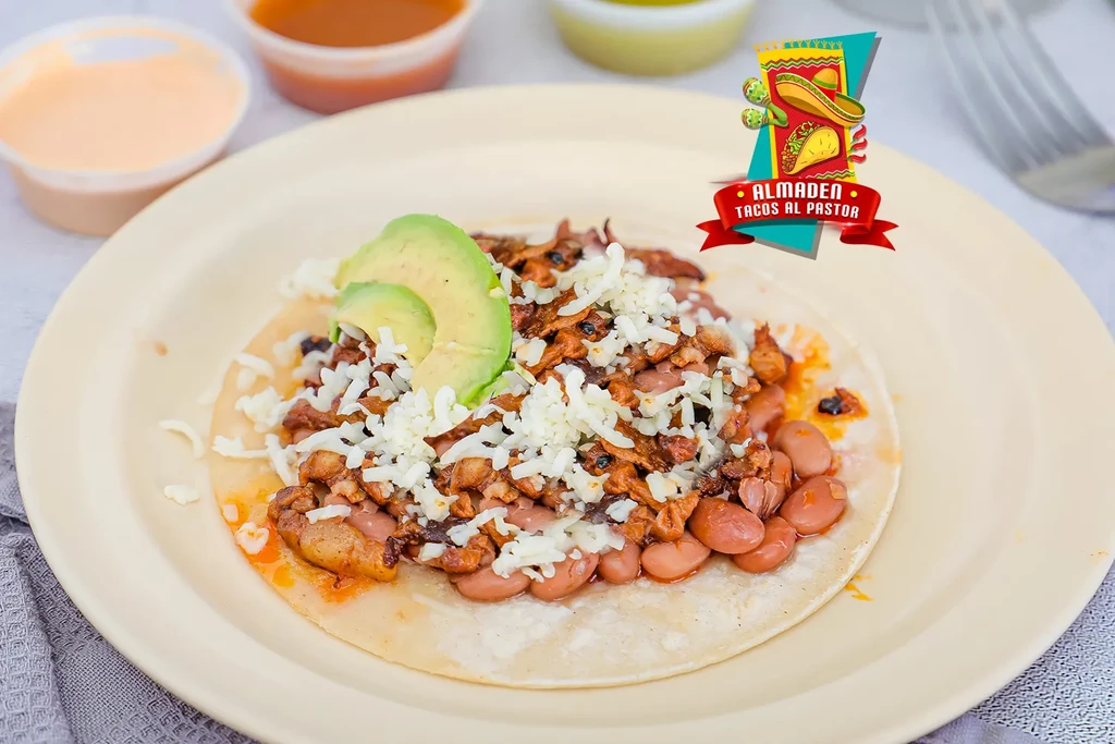 A close-up of a taco with meat, beans, cheese, and avocado.