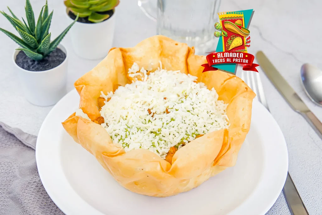 A crispy fried tortilla bowl filled with shredded cheese and meat.
