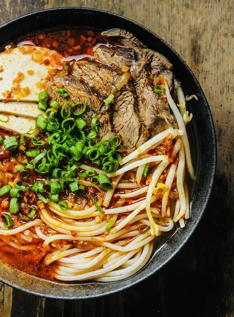 An overhead view of a bowl of spicy noodle soup.