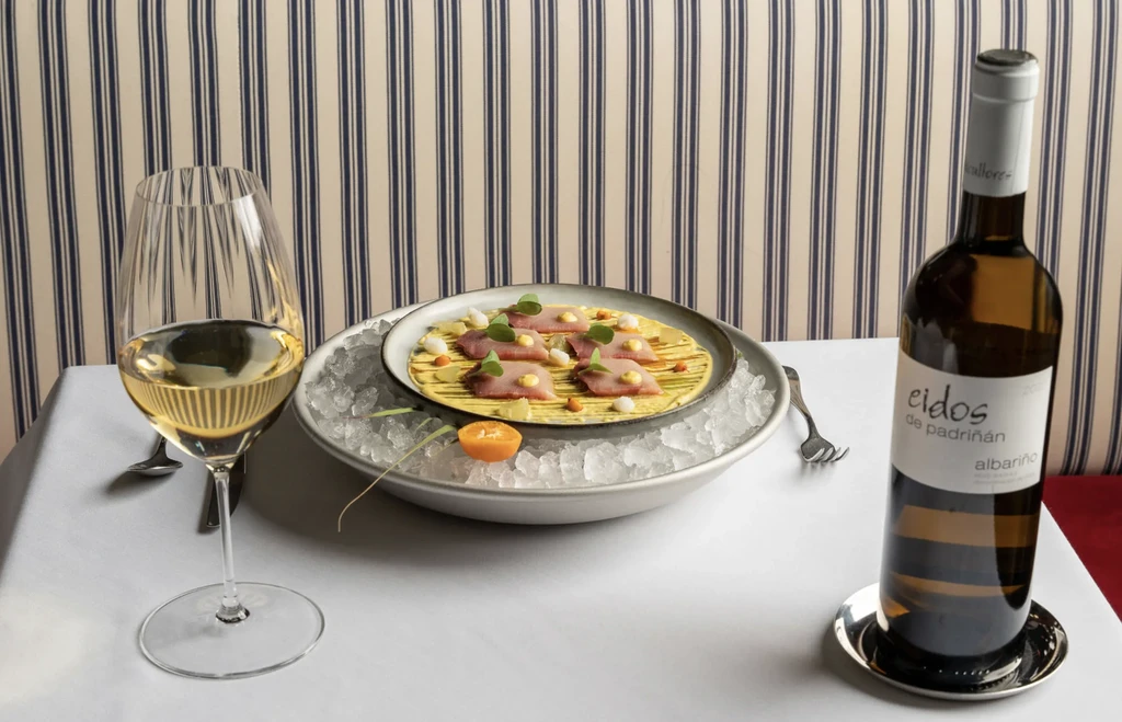 Albarino wine bottle and glass with tuna carpaccio on a bed of ice.