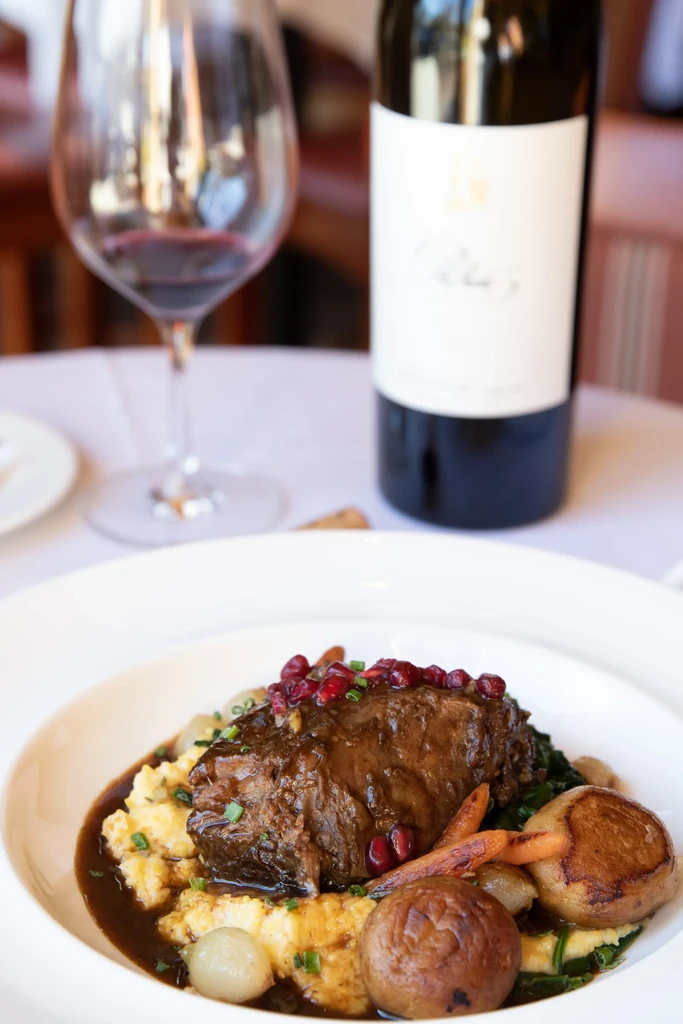 Braised short ribs with polenta, pomegranate, vegetables, and a bottle of wine.