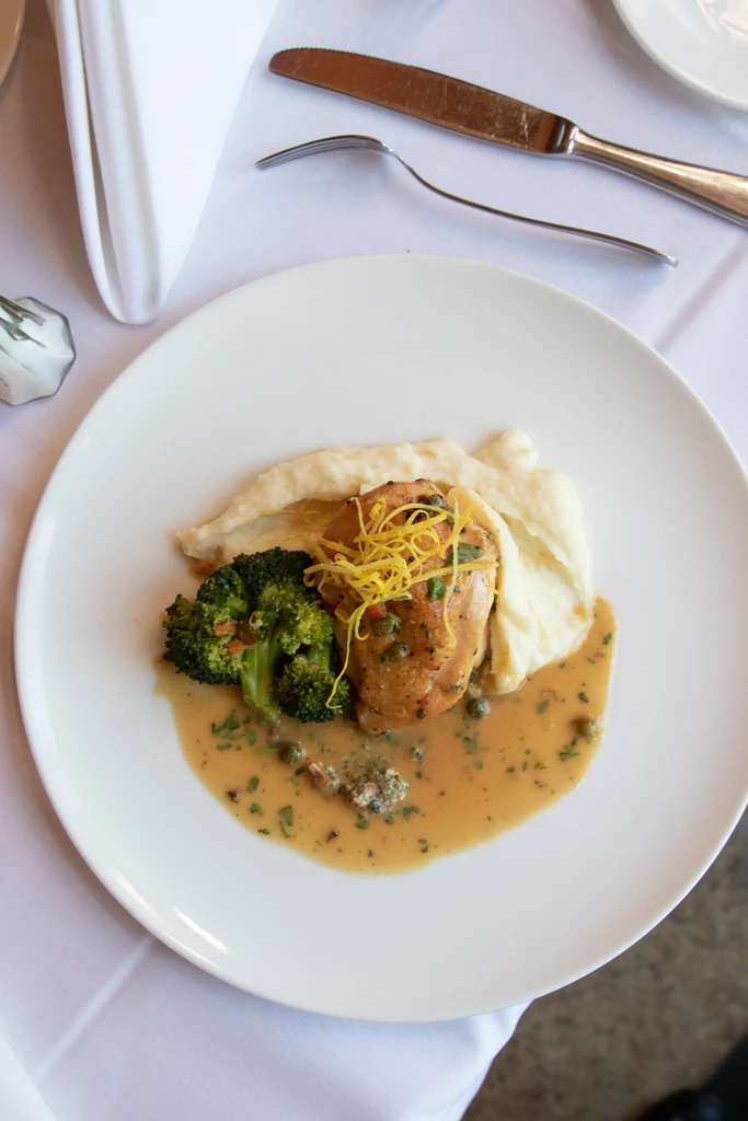 Chicken with mashed potatoes, broccoli, and a light brown sauce.