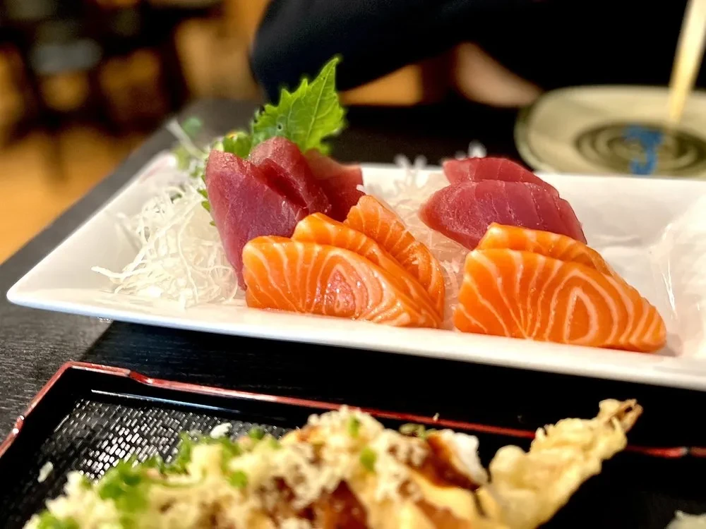 Salmon and tuna sashimi served on a white rectangular plate.