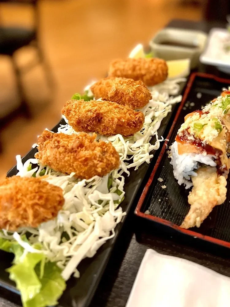 Fried food, cabbage, and sushi on two black platters.