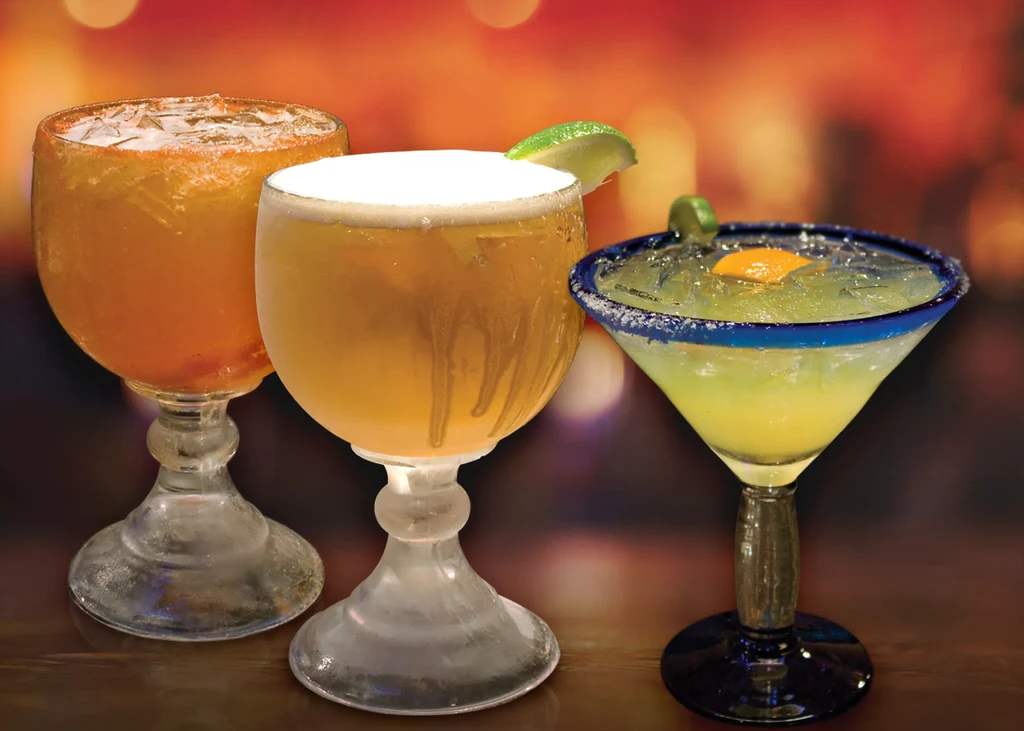 Three glasses with drinks: two beer, one margarita.