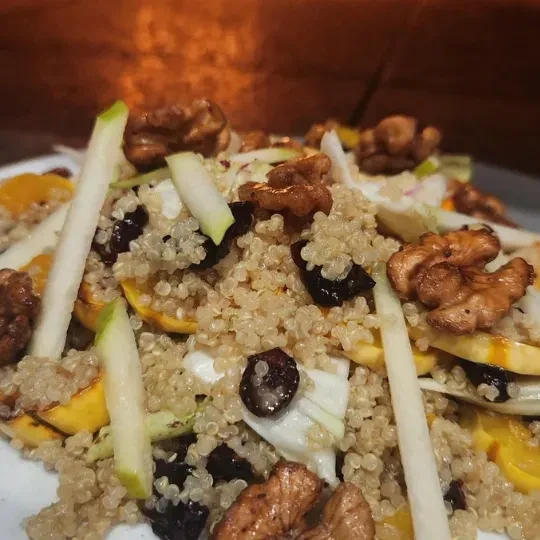 Close-up of colorful quinoa salad with squash, dried fruit, and walnuts.