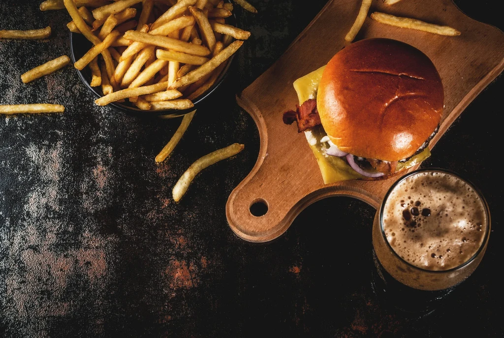 Burger, fries, and dark beer on a rustic dark table.
