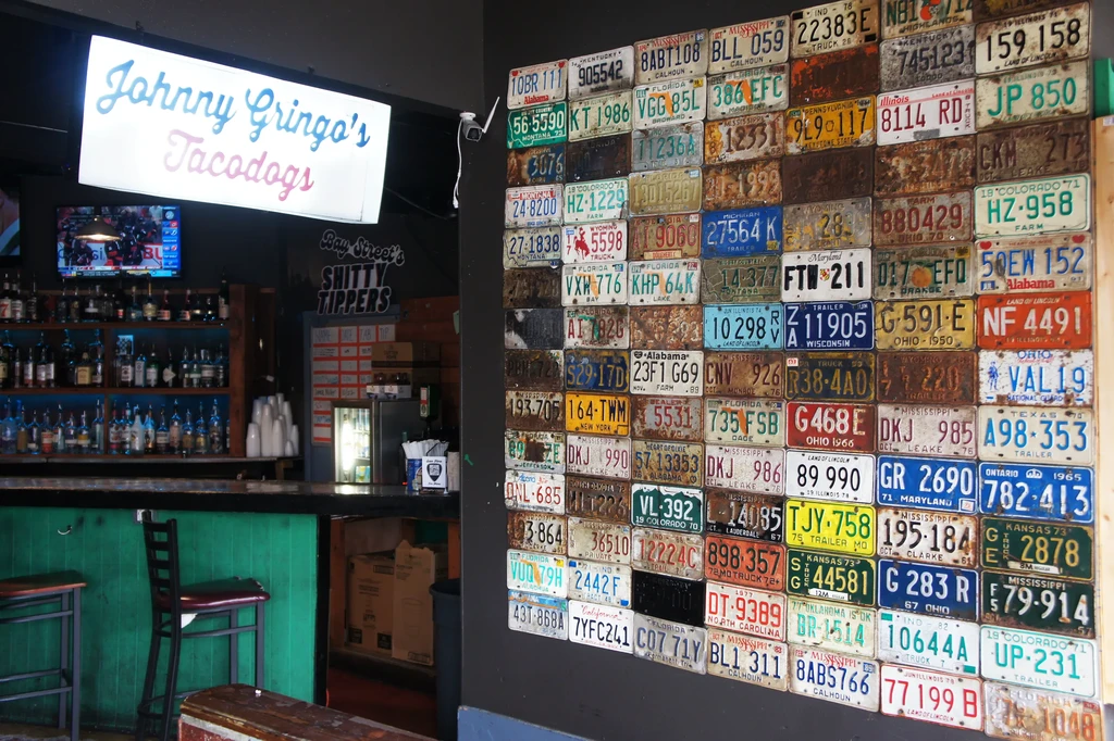 Casual bar interior with liquor shelves and a wall of vintage license plates.