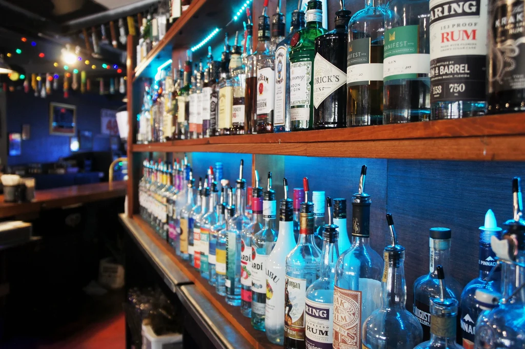Well-stocked bar shelves with liquor bottles illuminated by blue LED lights.