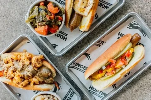 Overhead: HOPTIGER hot dogs with diverse toppings and two side dishes.