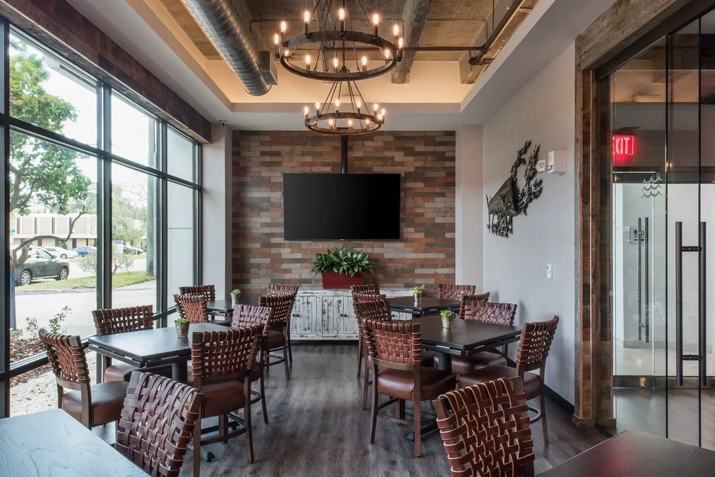 Empty modern restaurant interior with leather chairs and brick wall.