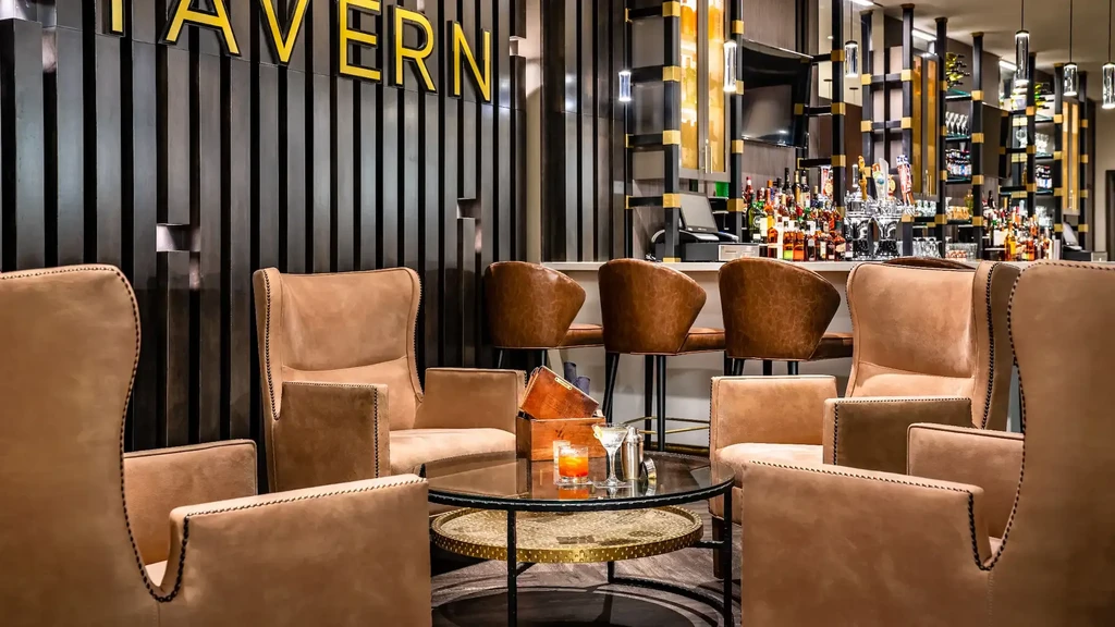 Modern bar interior with armchairs, two cocktails, and stocked bar.