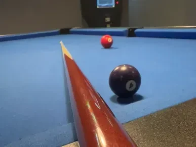Pool cue aims at a #4 and #7 ball on blue felt.