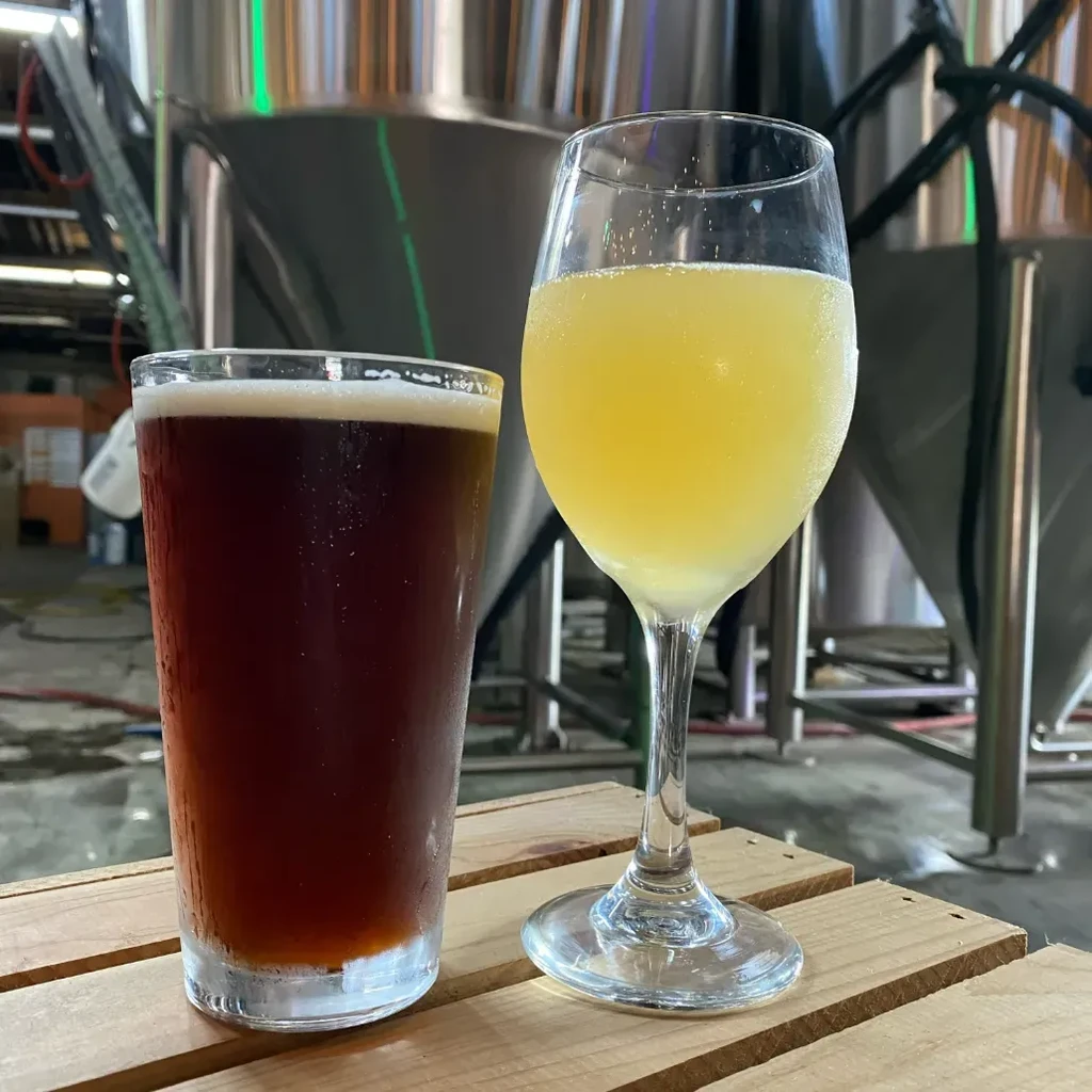 Two cold drinks in different glasses inside a brewery.
