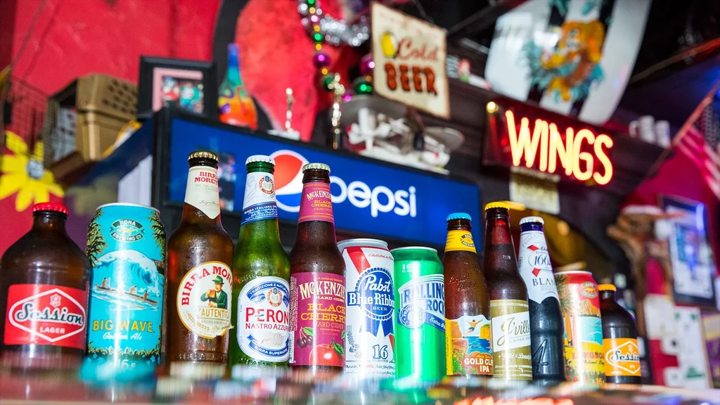 Cold bottled and canned alcoholic beverages on a reflective bar.