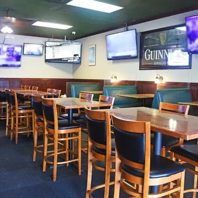 Empty pub dining area with high-top tables, booths, TVs, and Guinness sign.