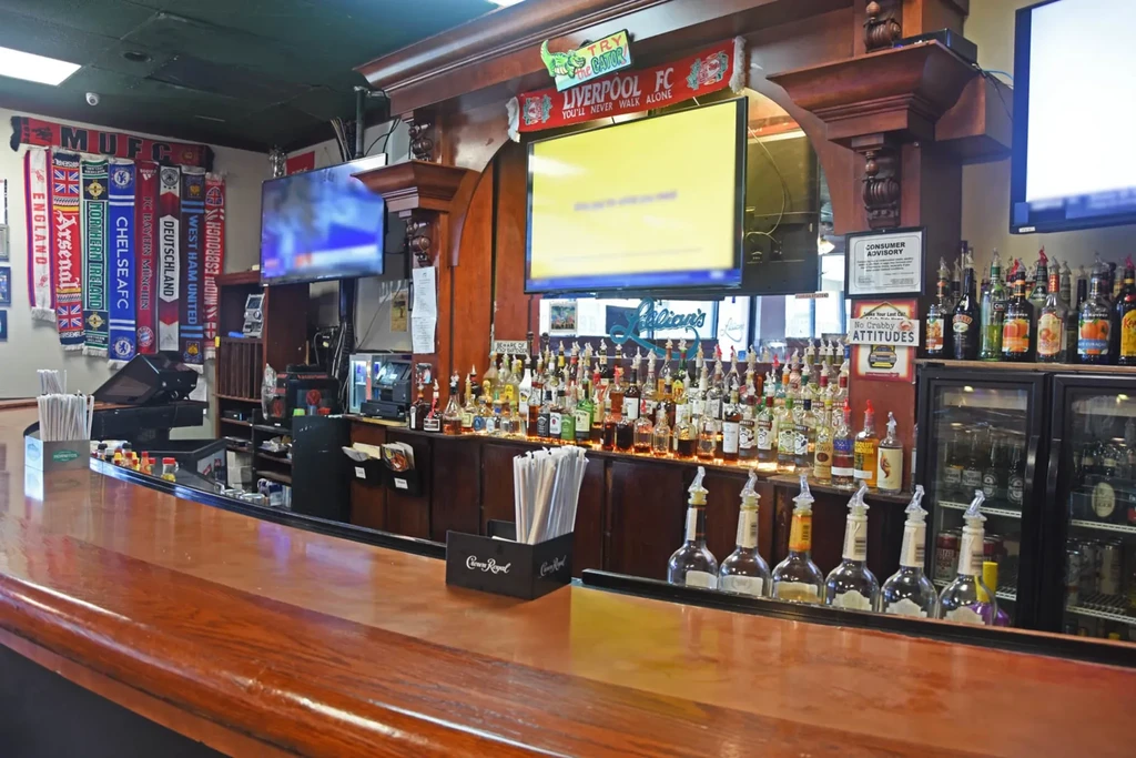 Empty sports bar with a long wooden bar and hanging soccer scarves.