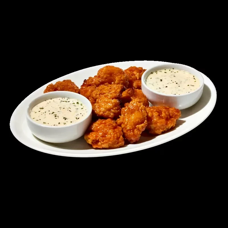 Reddish-orange glazed boneless chicken wings with two herb-garnished sauces.