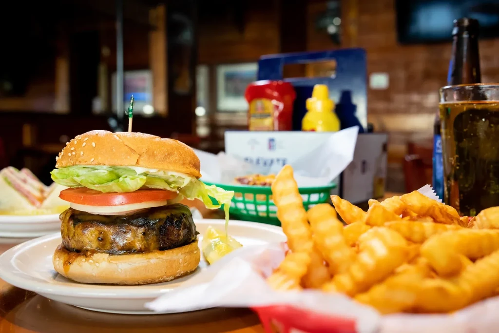 Well-lit hamburger and crinkle-cut fries on a restaurant table.