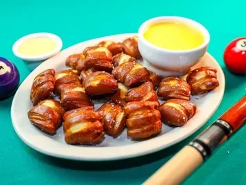 Pretzel bites with cheese sauce on a pool table with pool balls.