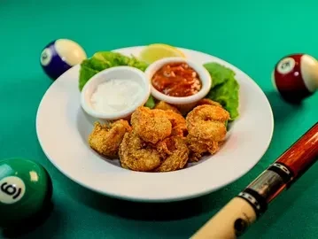 Fried shrimp, sauces, lemon on a pool table with pool balls.