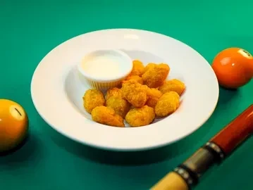 Fried food and dip on a plate, on a pool table.