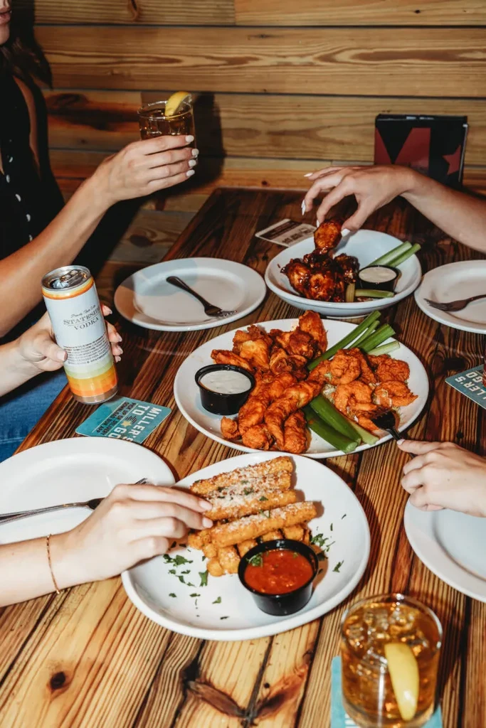 People share wings, tenders, and mozzarella sticks with cocktails.