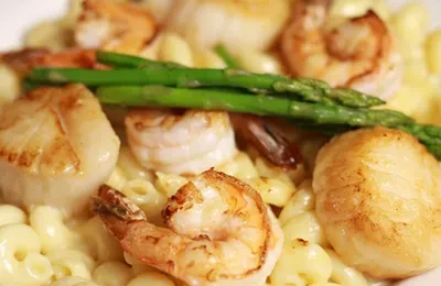 Creamy macaroni and cheese with seared scallops, shrimp, and asparagus.