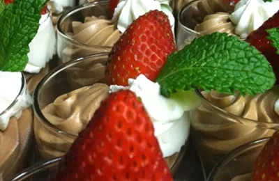 Individual chocolate mousse cups with whipped cream, strawberry, and mint.