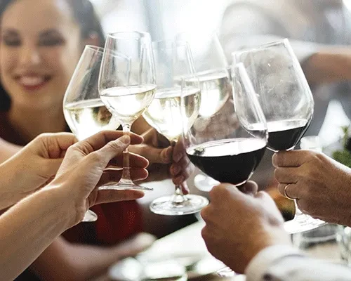 A close-up of diverse hands clinking wine glasses for a toast.