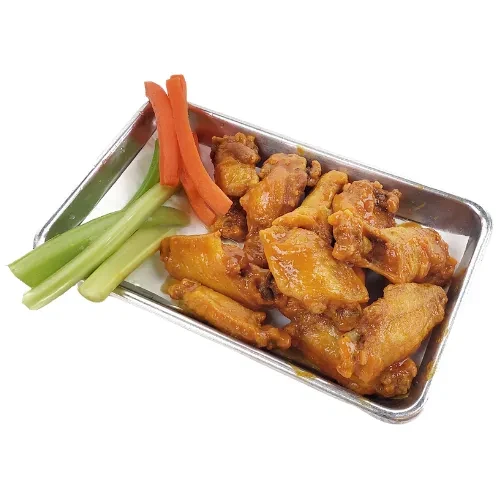 Sauced chicken wings, celery, and carrots in a metal tray on white.