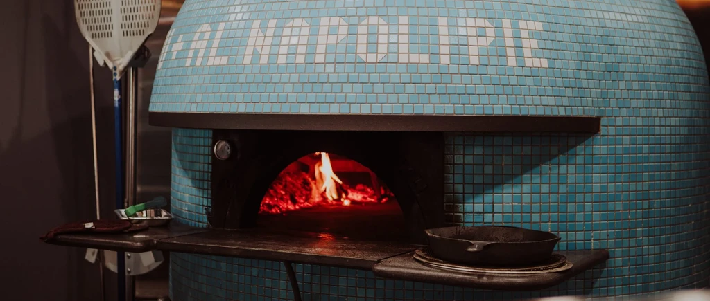Blue mosaic pizza oven spells NAPOLI with blazing fire.