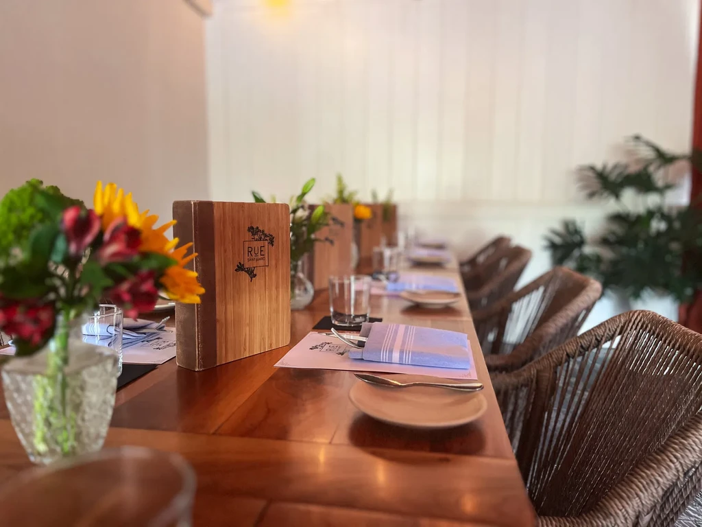Long polished wooden dining table set with Rue Saint-Marc menus and flowers.