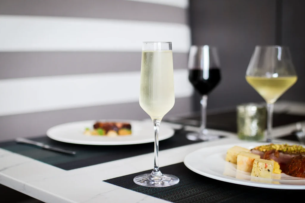 Sparkling drink in flute glass, food plates on a modern restaurant table.