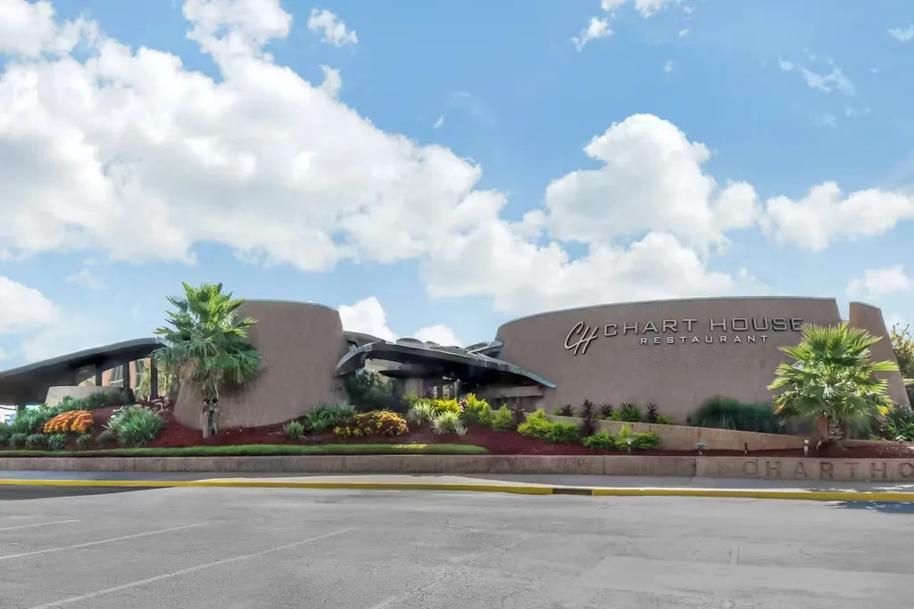 Chart House Restaurant exterior: modern stucco building, palm trees, and parking lot.