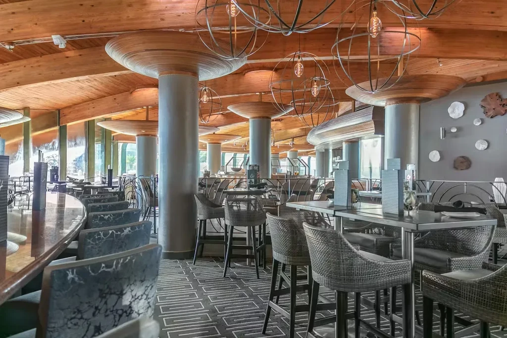 Empty upscale modern restaurant interior, wood beams, grey columns, sphere chandeliers.