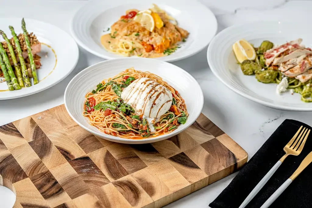 Overhead photo of four distinct, plated main course dishes on marble.