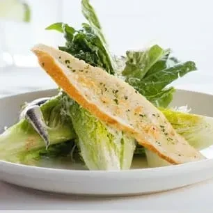 Caesar salad with romaine lettuce, creamy dressing, large crouton, and anchovy.