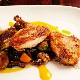Crispy roasted chicken, roasted vegetables, walnuts, and vibrant yellow sauce.