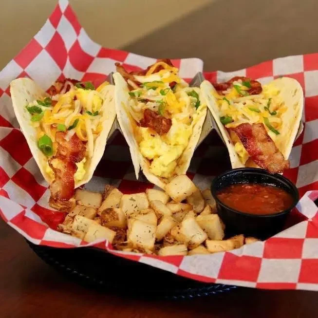 Three egg and bacon breakfast tacos with potatoes and salsa.
