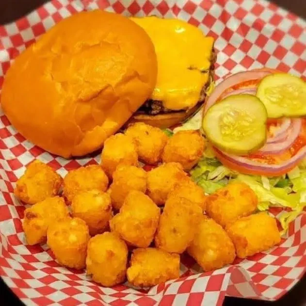 Deconstructed cheeseburger, golden tater tots in a checkered basket.