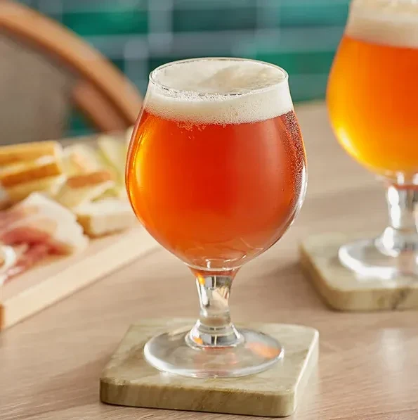 Close-up of a frothy amber beer and charcuterie spread.