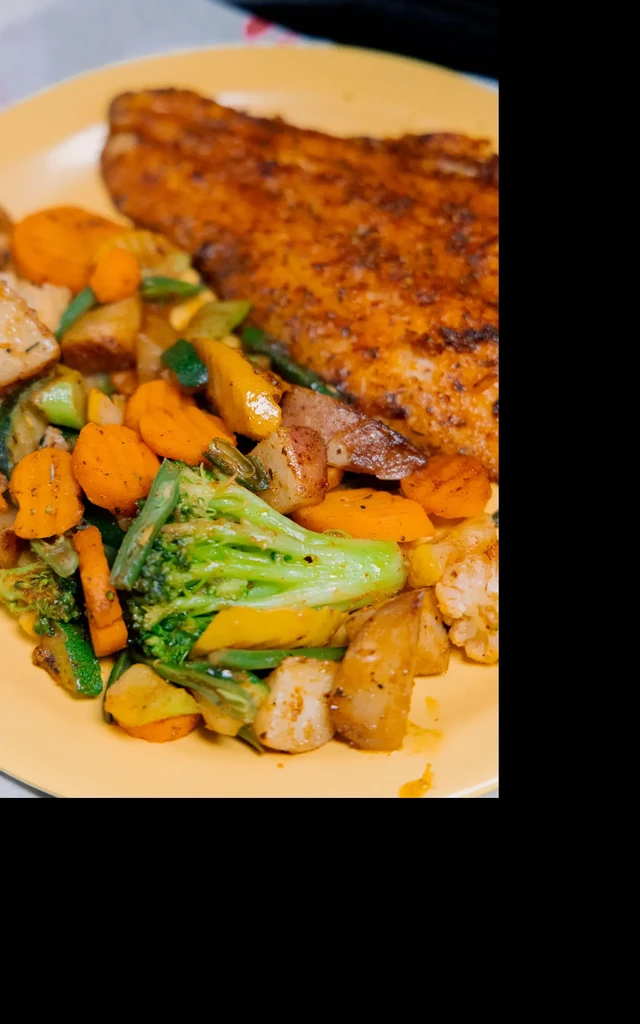 Yellow plate with seasoned fillet and colorful roasted vegetables.